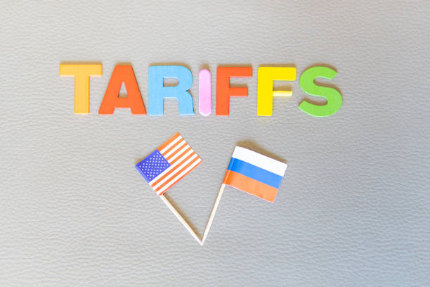 U.S.-Russia Tariffs Word (TARIFFS) and Russian and U.S. flags. Copy space on textured background. U.S. trade policy. Horizontal photo. Trump game