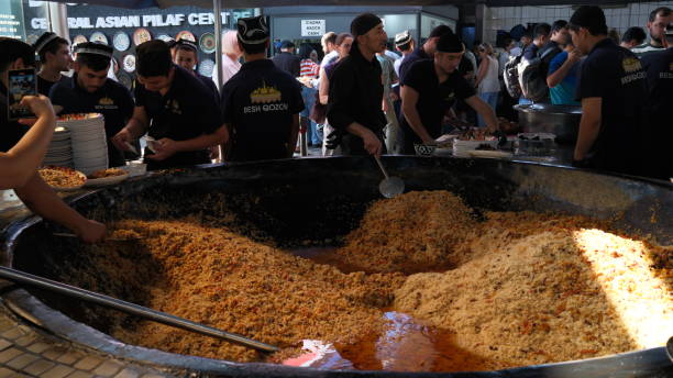 Tashkent, Uzbekistan - September 29 2024: chef fired the plov or pilau in kitchen. Plov is one of famous food in Central Asia which recipe usually involves cooking in stock or broth, adding spices