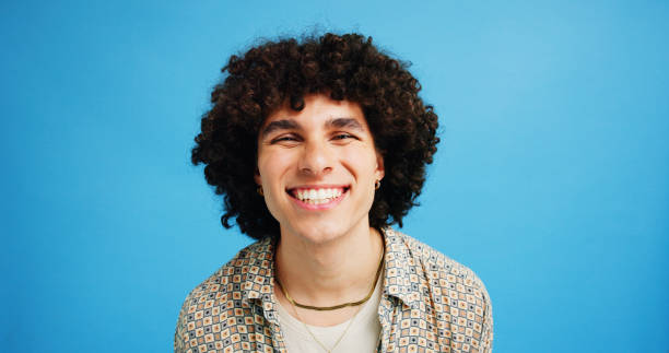 istock Studio, happy man or portrait with fashion for funky style, cool expression or confidence for afro. Blue background, male person or hipster model with clothes for new year party, curly hair or mockup 2197604776