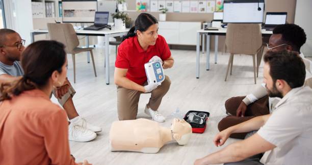 istock Mannequin, cpr and training with people and defibrillator for first aid workshop, cardiac arrest rescue or safety protocol. Healthcare class, medical simulation and heart rhythm with paramedic course 2197609544