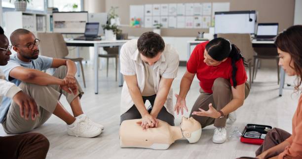 istock First aid, learning cpr and group with dummy for safety compliance, health and chest compression for breathing. Paramedic course, medical and teaching people emergency rescue technique in office 2197609548