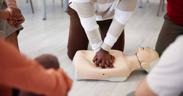 istock People, dummy or hands in office for first aid, CPR workshop or chest compression lesson. Colleagues, emergency practice or mannequin in agency for life saving procedure, demo and employee engagement 2197609551