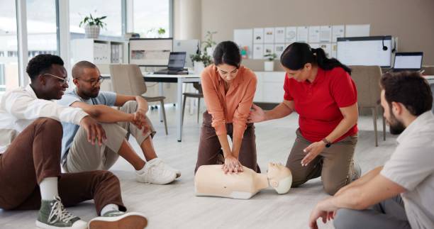 istock First aid, cpr training and group with dummy for safety compliance, health and chest compression for breathing. Paramedic course, learning and teaching people emergency rescue technique in office 2197609556