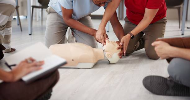 istock People, mannequin and hands in office for first aid, CPR workshop and choking prevention lesson. Team, emergency practice and dummy in agency for open airways procedure, notes and employee engagement 2197609564