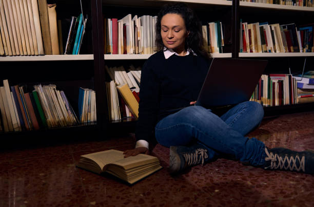istock Woman studying with a laptop and book in a library setting 2197609643