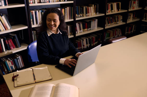 istock Smiling woman using a laptop in a library for studying or working 2197609670