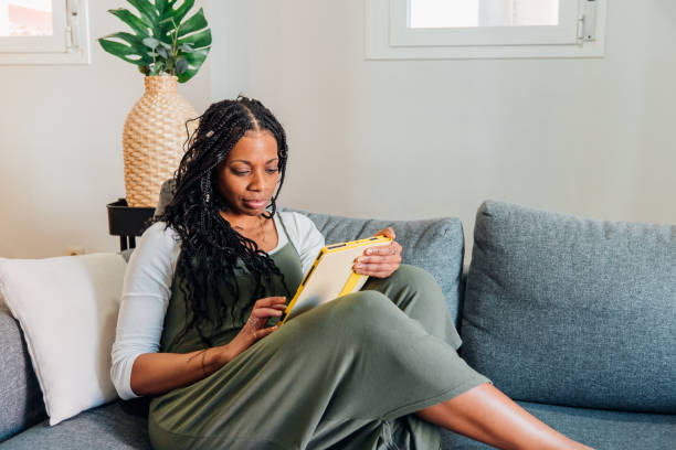 istock Casual-clad woman sitting on sofa, browsing digital tablet while relaxing in comfortable home living space 2197611752