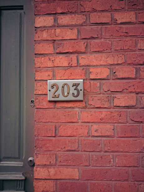 istock House number two hundred three (203) against a brick wall and door 2197613235