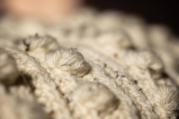 Macro photograph showcasing a textured and detailed beige yarn knit. Featuring intricate knitting with a soft and cozy appearance, perfect for illustrating fabric, crafting, and textile-related purposes.