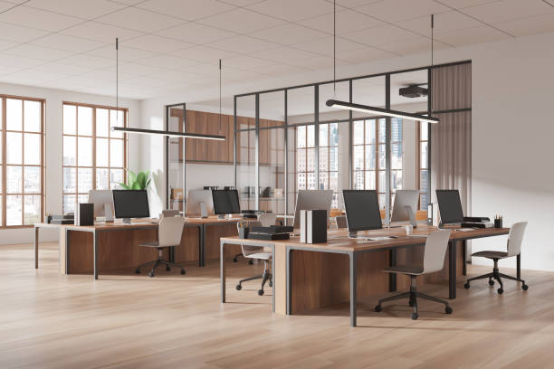 istock Modern open office space featuring desks with computers, wooden floors, large windows, and glass partitions in a bright business interior. 3D Rendering 2197617392