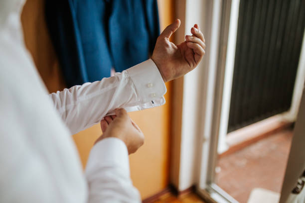 A groom fastening his cufflinks, preparing for his big day. The close-up shot captures the elegance and anticipation of the moment, highlighting attention to detail and formal attire.