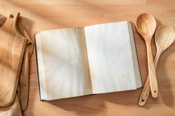 Open cookbook with blank pages shot from above on wooden table. Copy space on book. High resolution 42Mp studio digital capture taken with SONY A7rII and Zeiss Batis 40mm F2.0 CF lens