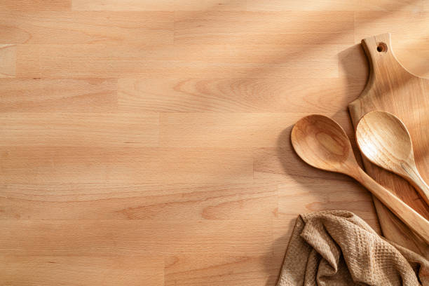 Wooden culinary background with two spoons, cutting board and a tablecloth at the right border making a frame and leaving copy space. High resolution 42Mp studio digital capture taken with SONY A7rII and Zeiss Batis 40mm F2.0 CF lens
