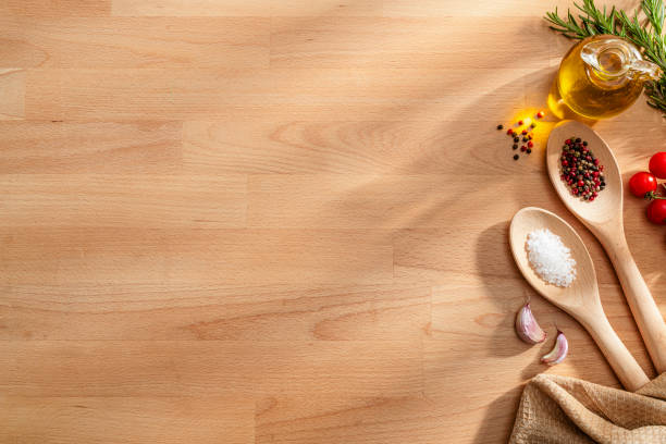 Cooking utensils and spices on wood table. The composition is at the right border making a frame and leaving copy space. High resolution 42Mp studio digital capture taken with SONY A7rII and Zeiss Batis 40mm F2.0 CF lens