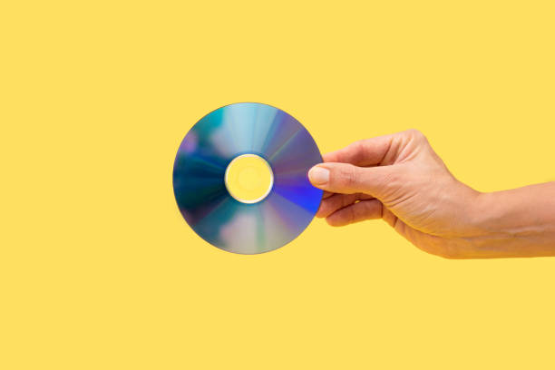 istock Hand holding compact disc on yellow background, music, data storage or nostalgic technology 2197619286