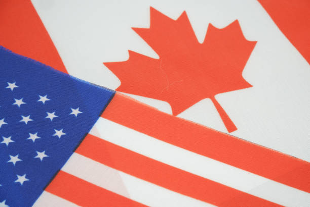 istock USA and Canadian flags close up. 2197619715