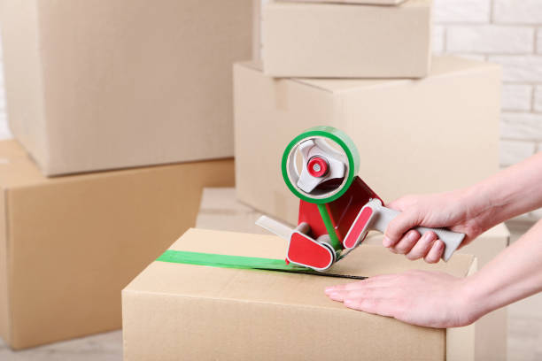 istock Female hands packaging cardboard box with dispenser 2197623831