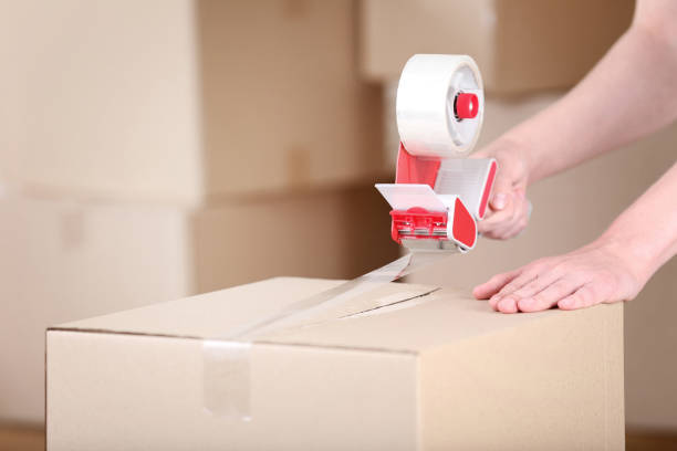 istock Female hands packaging cardboard box with dispenser 2197623973