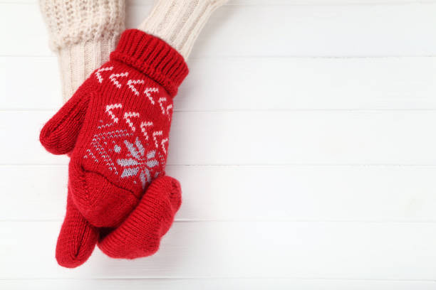 istock Hands in knitted mittens on white wooden table 2197628285