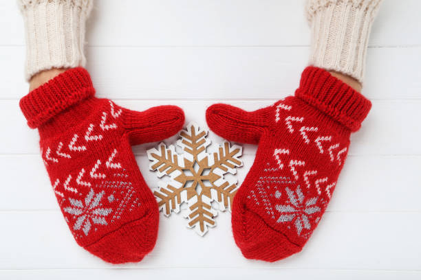 Hands in knitted mittens with snowflake on white wooden table