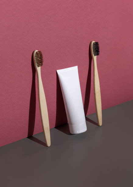istock Blank toothpaste tube and bamboo toothbrushes on grey and red, hard shadow closeup, mockup 2197628463