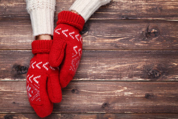 istock Hands in knitted mittens on brown wooden table 2197628610