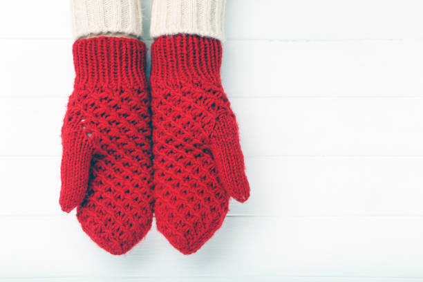 istock Hands in knitted mittens on white wooden table 2197628737