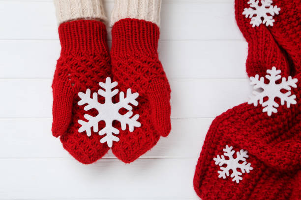istock Hands in knitted mittens holding snowflake on white wooden table 2197629408