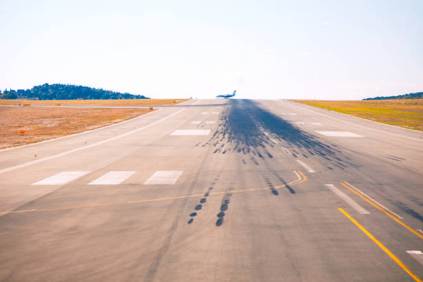 Long airport runway with tire skid marks leading to departing airplane in distance. Dynamic aviation scene capturing takeoff, motion, and travel, with clear skies and open space enhancing perspective