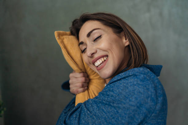 istock Young Woman Hugging a Pillow with Closed Eyes and Smiling 2197631785