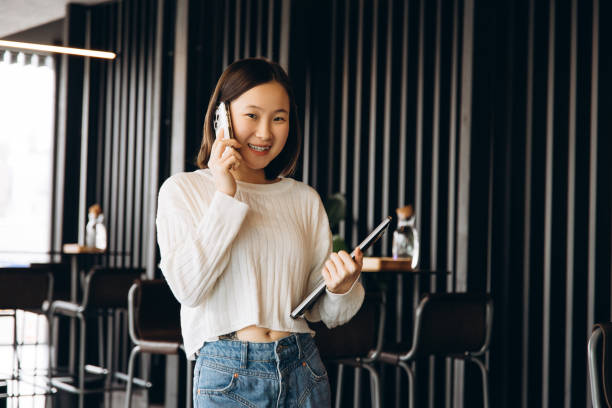 istock Young asian freelancer talking on phone and holding tablet in modern office 2197634137