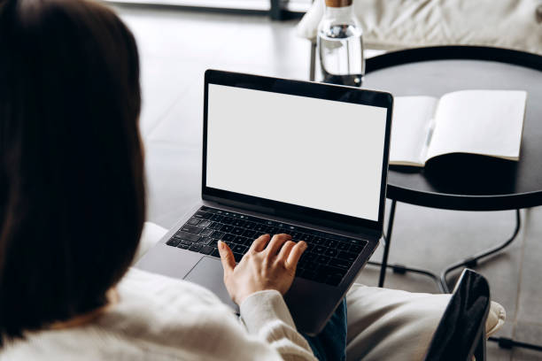 istock Woman working from home using laptop with blank screen mockup 2197634164