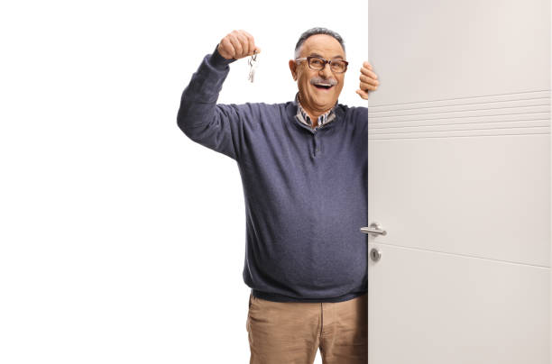 Excited mature man holding a key behind a door isolated on white background