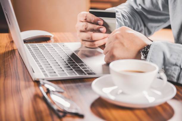 istock Man using laptop and holding credit card 2197634971