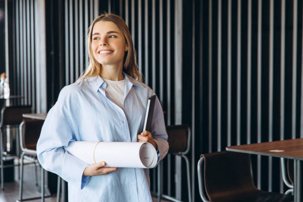 istock Smiling architect holding blueprints and tablet in modern office 2197635984