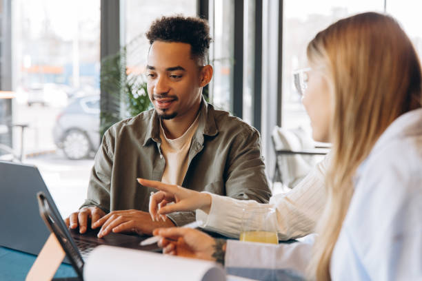 istock Coworkers discussing a project on a laptop in a cafe 2197636011
