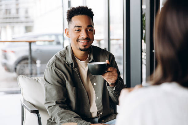 istock Young man enjoying coffee and conversation in cafe 2197636049