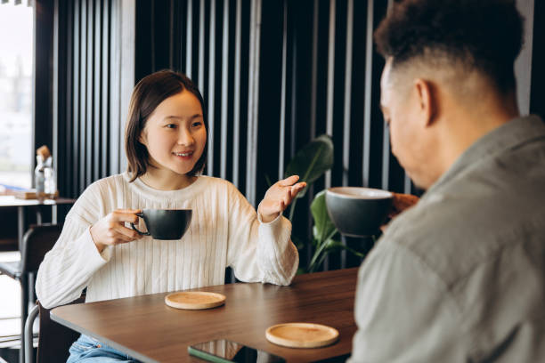 istock Young woman and man having coffee break and talking in modern cafe 2197636055