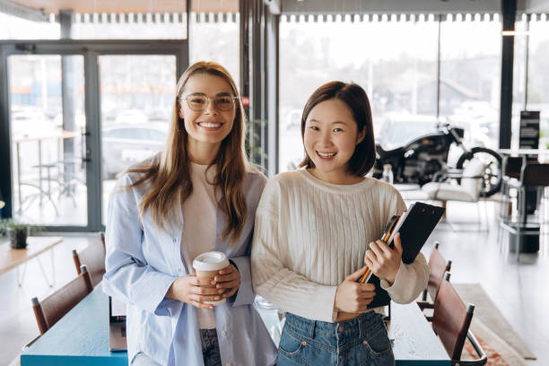 istock Two young businesswomen smiling in modern office with coffee and documents 2197636140
