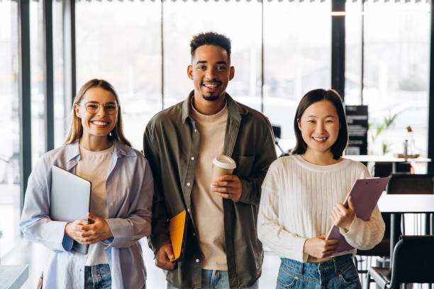 istock Happy multiethnic students holding laptop, book and clipboard smiling at campus 2197636147