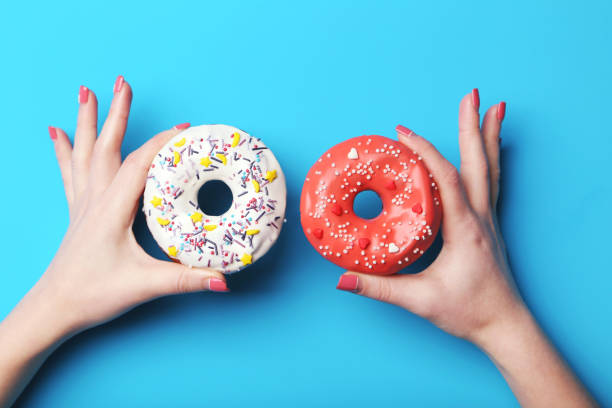 Female hands holding sweet donuts with sprinkles