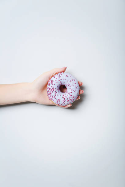 istock Female hand holding sweet donut on grey background 2197637120