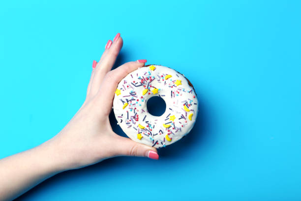 istock Female hand holding sweet donut with sprinkles 2197637271