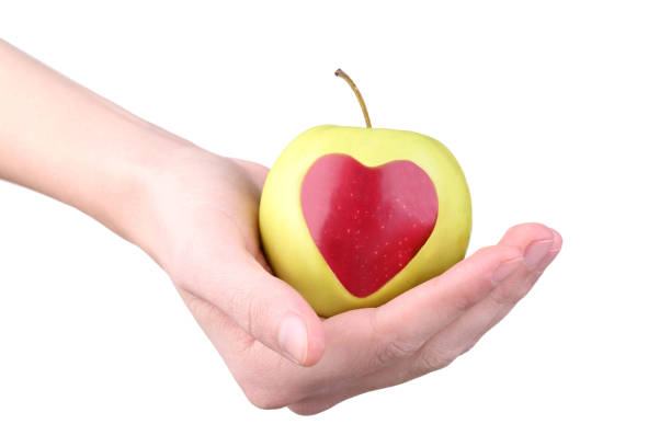 istock Female hands holding apple with cutout heart shape on white background 2197638520