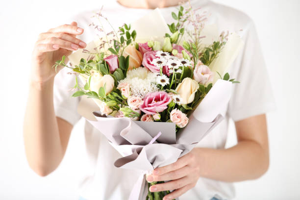 istock Female hands holding beautiful flower bouquet on white background 2197639348