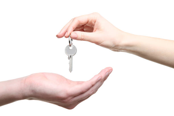 istock Female hand holding house key on white background 2197639728