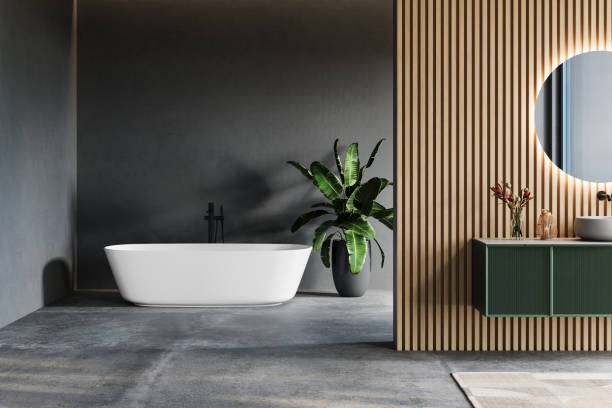 istock Modern bathroom interior with a freestanding bathtub, wooden slatted wall, round backlit mirror, and green floating vanity near a large window. 3D rendering. 2197640548