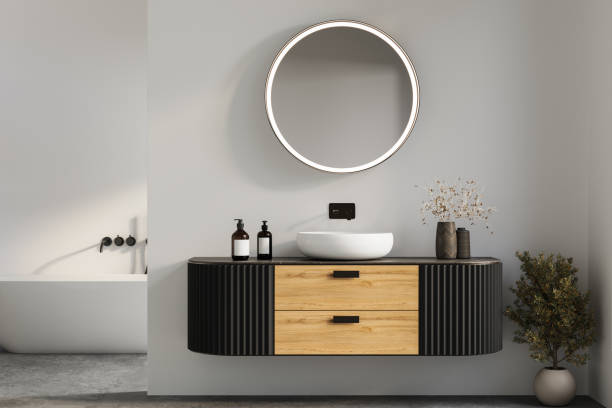 istock Stylish bathroom vanity with wood and black paneling, round illuminated mirror, and modern vessel sink, complemented by natural decor. 3D rendering 2197640725