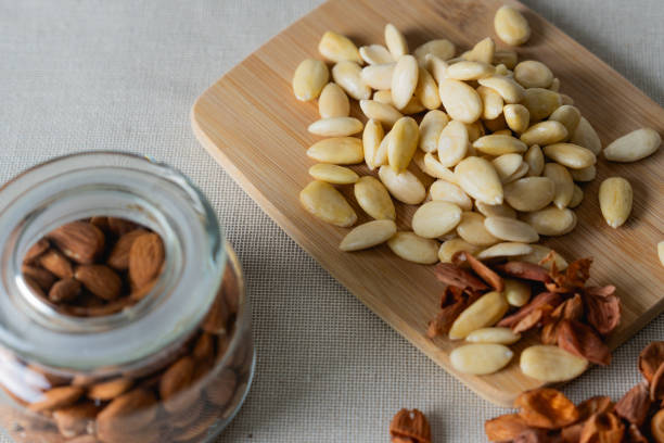 Stock photo showing close-up, elevated view of a pile of almonds and pumpkin seeds, also known as pepita. These nuts and seeds are considered to be a very healthy snack food as they all contain antioxidants and protein, and boast a list of health benefits.