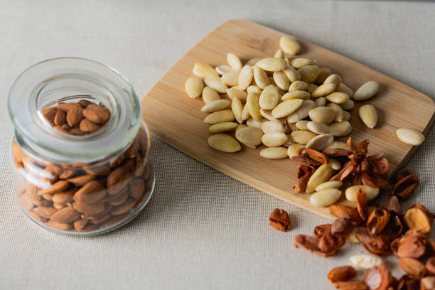 Stock photo showing close-up view of a pile of almonds, cashews and pumpkin seeds, also known as pepita. Raw cashews are actually unsafe to eat due to containing urushiol which is toxic and can cause skin irritation. Therefore, 'raw' cashews sold in stores have actually been cooked to remove the urushiol and once this is done are considered to be a very healthy snack food along with almonds and pumpkin seeds as they all contain antioxidants and protein, and boast a list of health benefits.
